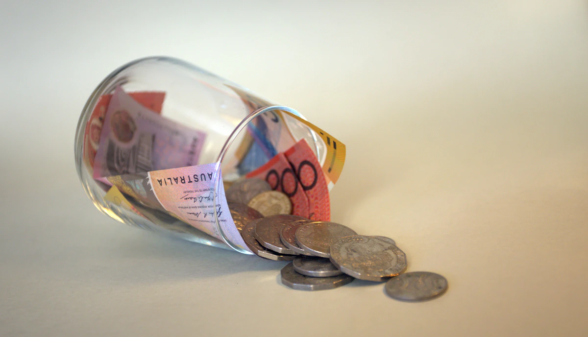 Coins and banknotes spilling from a clear glass jar