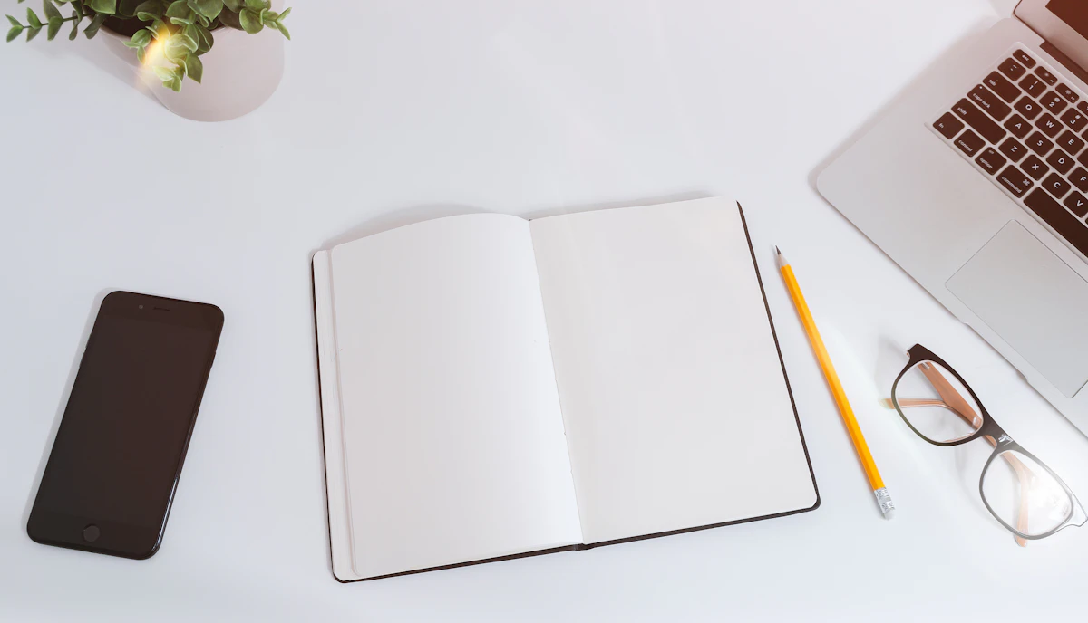 A work desk with a notebook, pencil and laptop