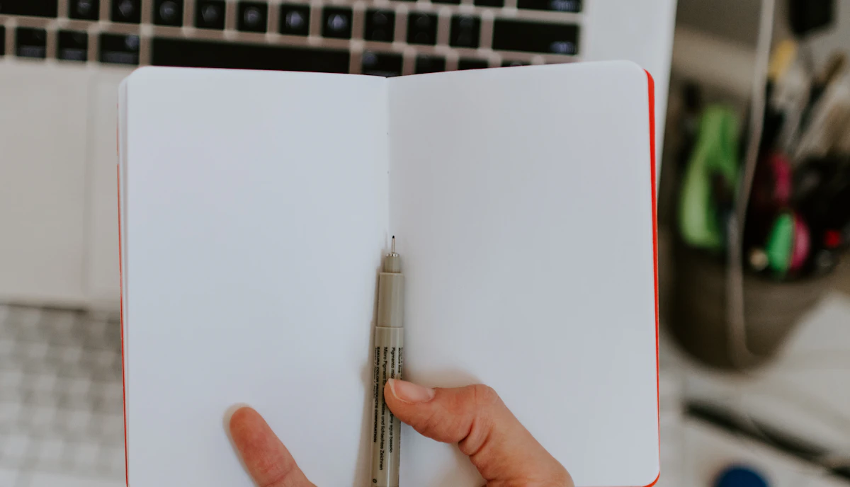 Boş bir defter ve kalem tutan eller